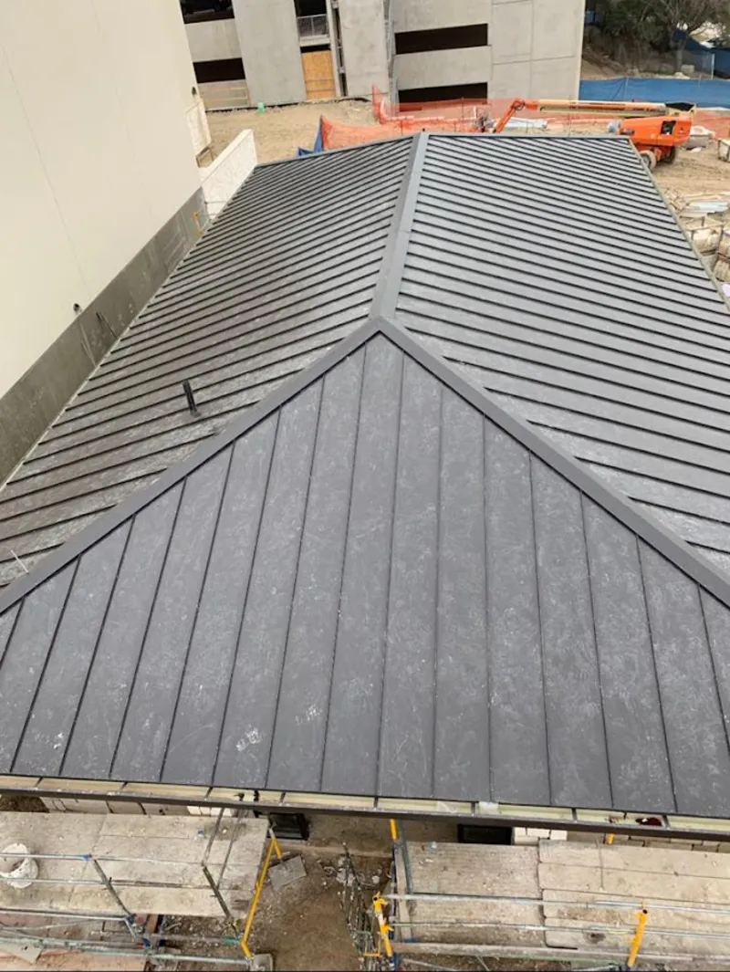 Commercial metal roof construction with crane equipment in Highlands Ranch